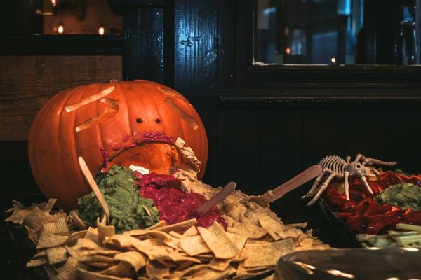 halloween themed grazing board decorated with carved pumpkin and spooky decorations