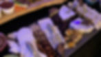 A gourmet spread with various cheeses, nuts, fruits, and chutney on wooden platters. Bowls of olives and pickled items add colour. Grazing board.