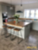 Stylish modern kitchen renovation by SELFIX BUILDERS LTD featuring light gray cabinets, wood island with stools, stainless steel appliances, and pendant lighting