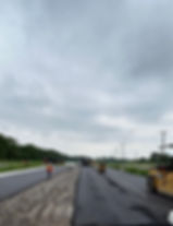 Construction workers and heavy machinery working on laying down road