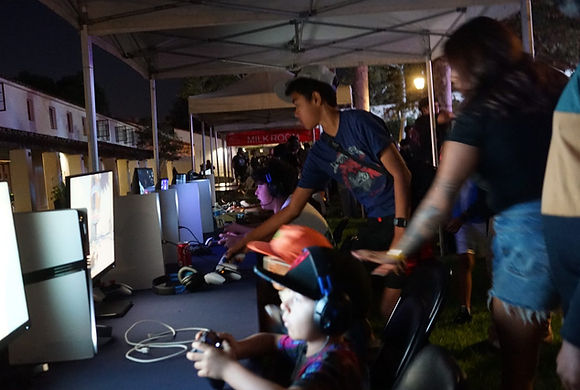 Guests playing at a long, lit row of GameLand stations under canopies at night