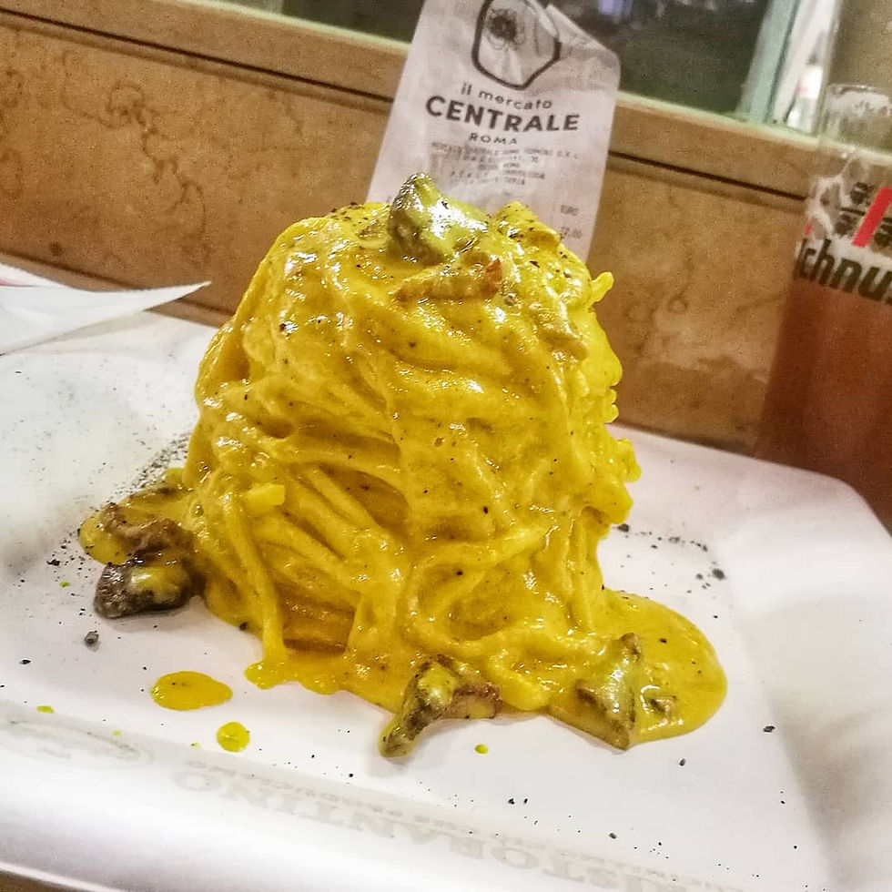 Plate of creamy carbonara pasta served at Mercato Centrale Roma, topped with black pepper and guanciale.