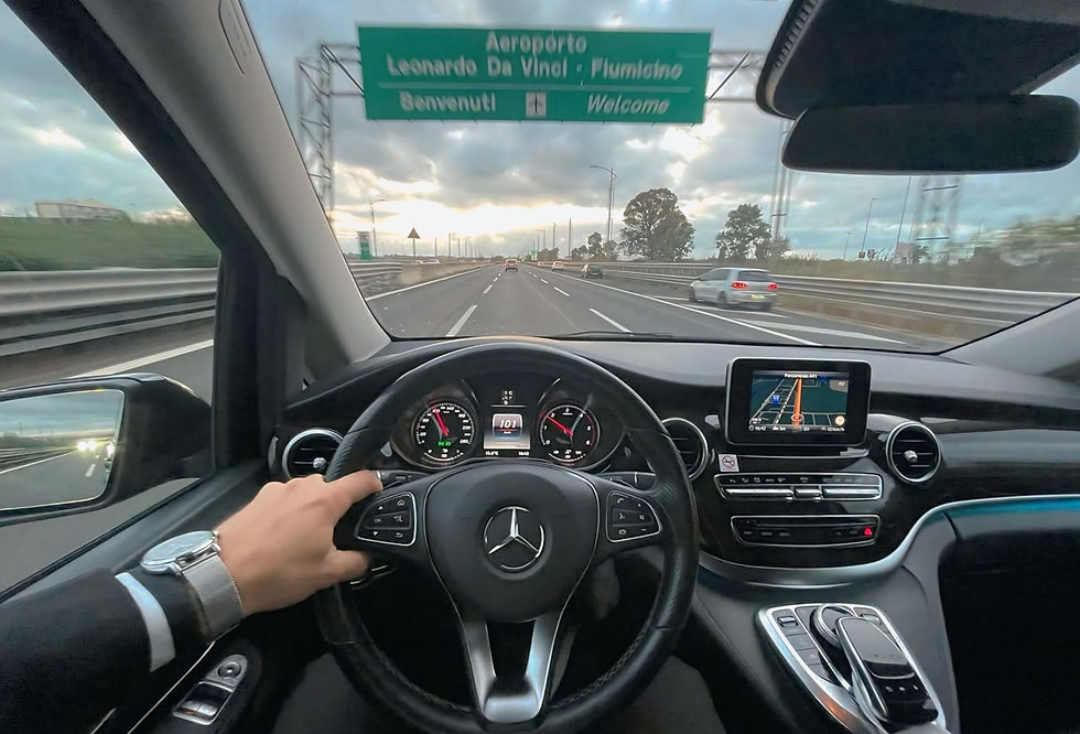 View from inside a private transfer car on the highway during a Fiumicino Airport to Rome city centre transfer, showing the steering wheel, navigation screen, and road sign for Leonardo Da Vinci – Fiumicino. Photo: dfcar_e_boatmultiservice