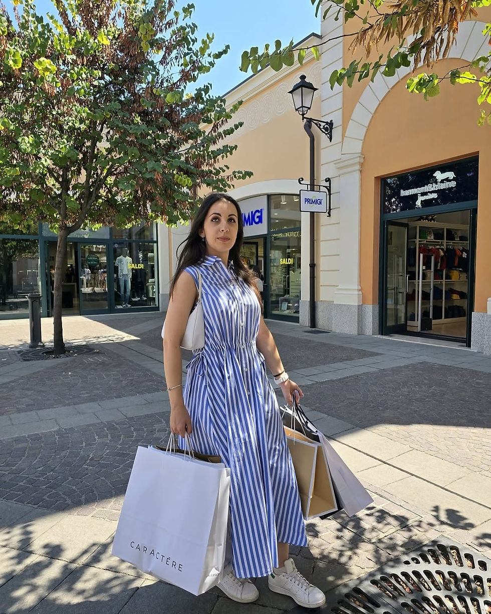 A woman walks through Castel Romano Designer Outlet with Caractère and other shopping bags in hand, illustrating a successful day of outlet shopping in Rome.