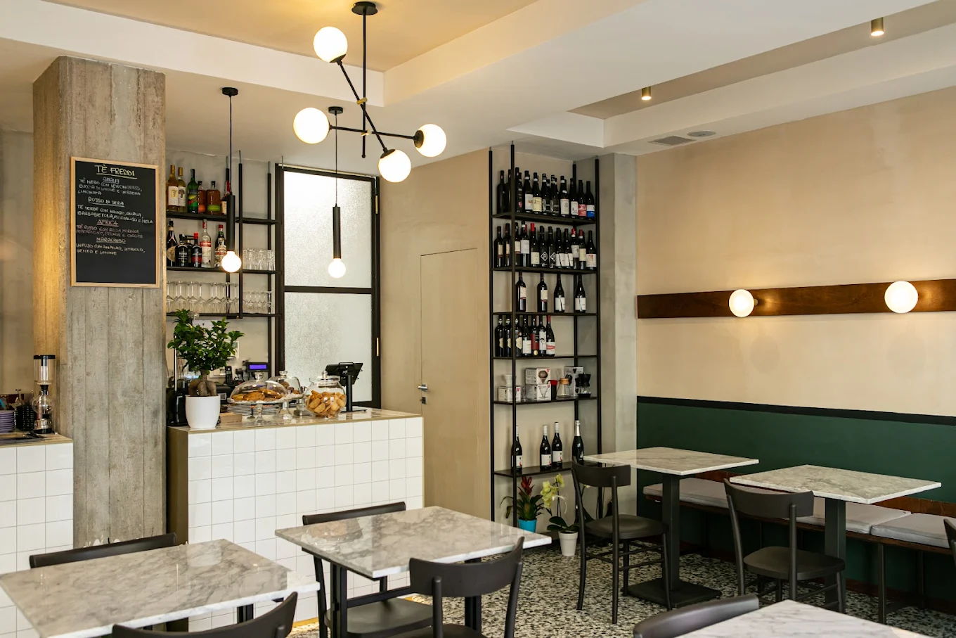 Interior of MAE cafe in Prati, Rome, showing minimalist design, wine shelves, and marble tables. Photo by MAE.