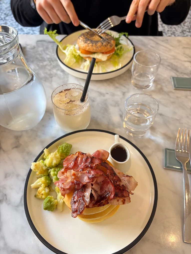 Brunch dishes at MAE in Prati, featuring pancakes with bacon and a smoked salmon bagel. Photo by Matteo.