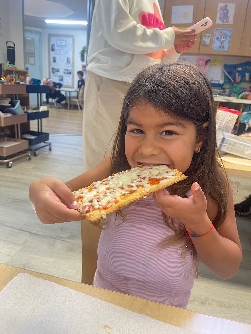 Student enjoying a slice of matza pizza during a Passover Camp activity at Sinai.