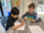 Sinai Learning Lab students working on reading and writing activities together at a classroom table.