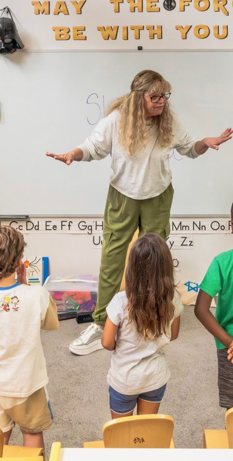 Teacher leading young students during a classroom learning activity at Temple Sinai youth programs.
