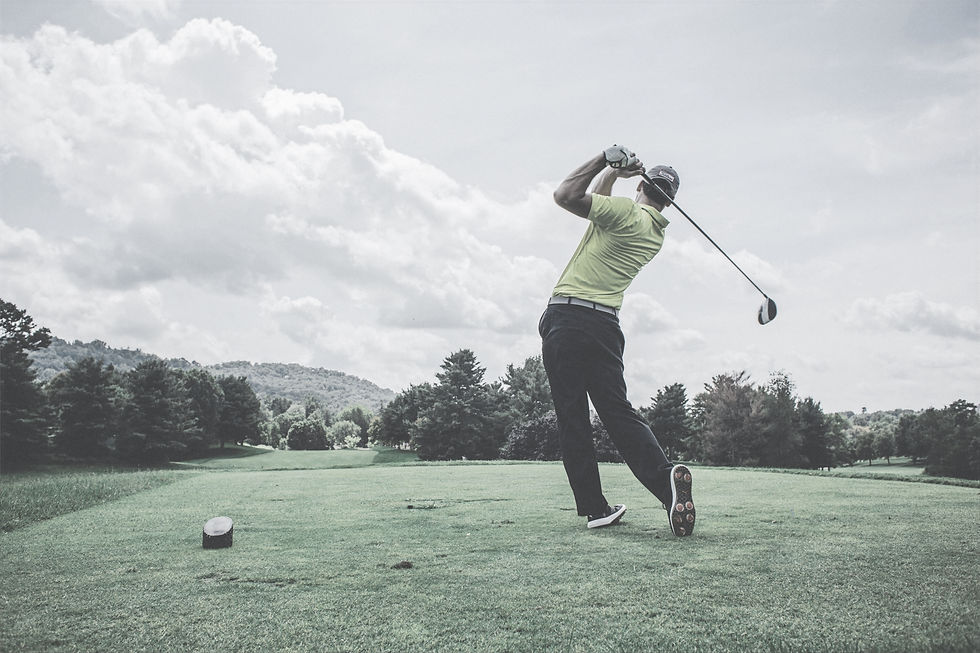 Man swinging a golf club from the green turf of a high-definition indoor simulator bay at Back Nine Tavern