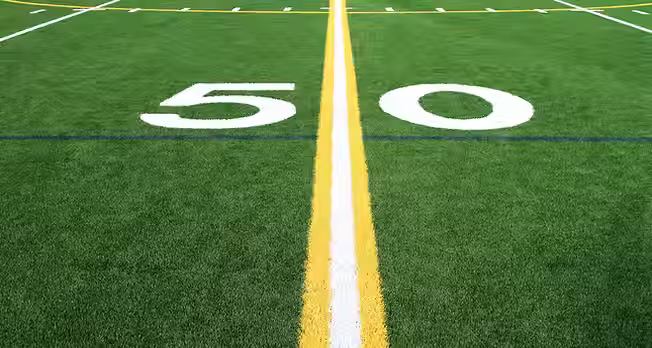 The 50-yard line marking on a green football field