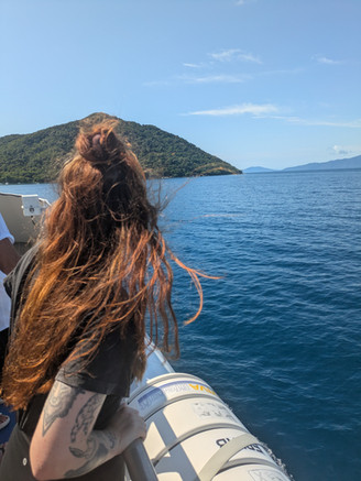 A woman peering over the edge of a boat looking over the water