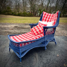 Blue wicker chaise lounge with red and white plaid pattern cushions.