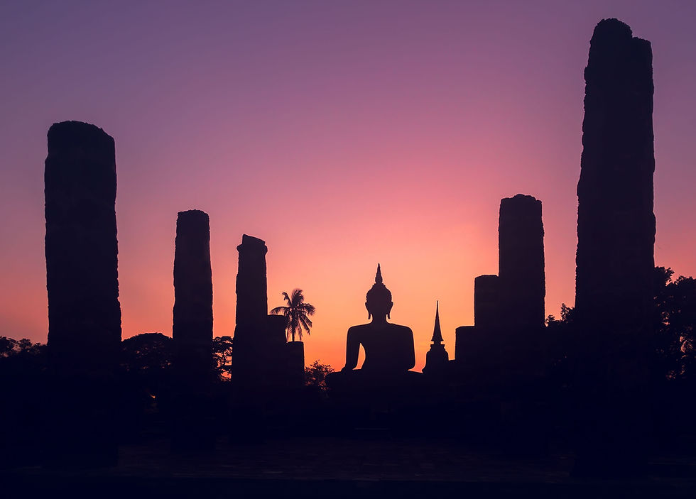 Silhouetted Buddha statue and ancient temple pillars at sunset, with a pink-orange-purple sky and palm tree silhouette