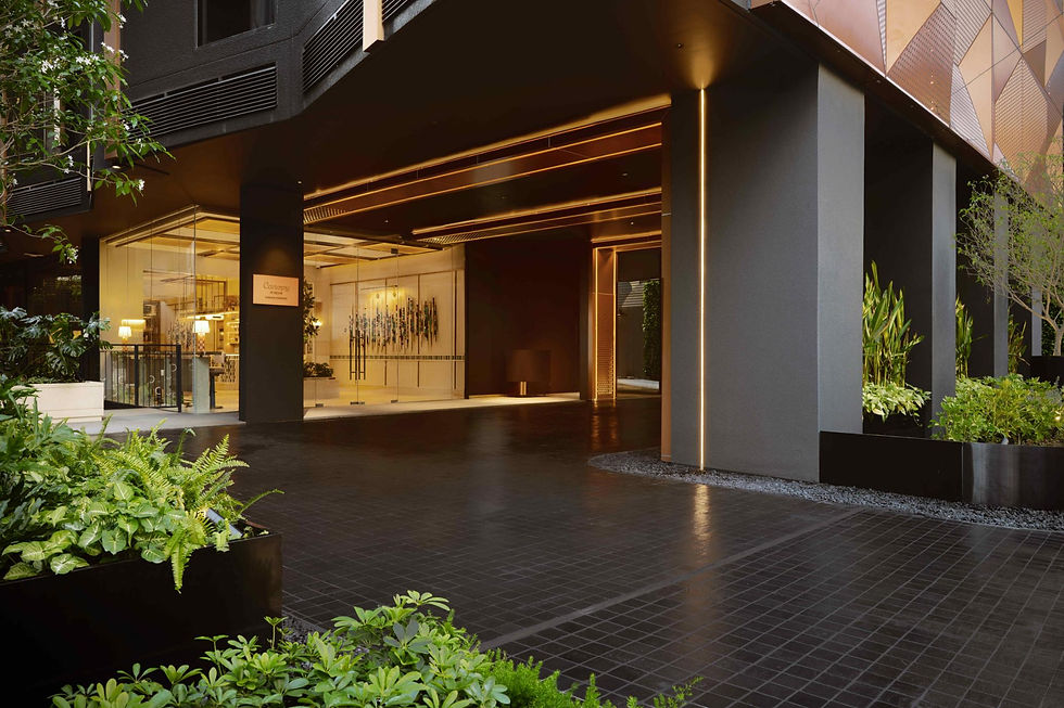 Modern hotel entrance with glowing black-and-gold facade, lush planters, and a Canopy by Hilton sign in a calm courtyard