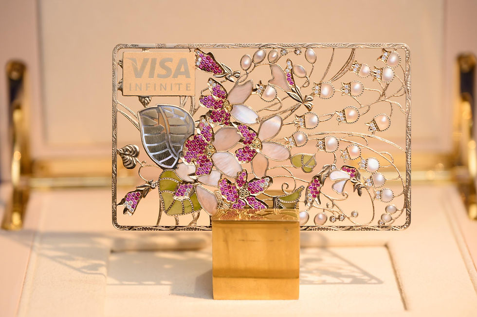 Jeweled Visa Infinite card with floral pearl-and-gem pattern displayed on a gold stand against a warm showroom background.