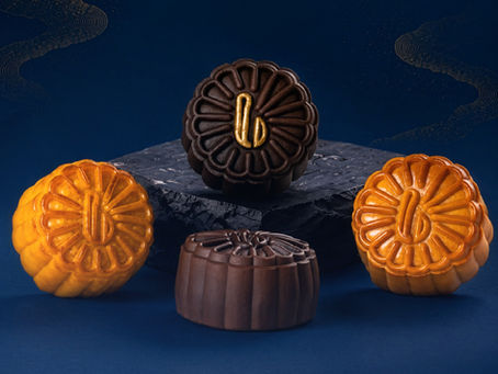 Four mooncakes in orange and chocolate tones on a dark blue background, arranged around a stone slab.