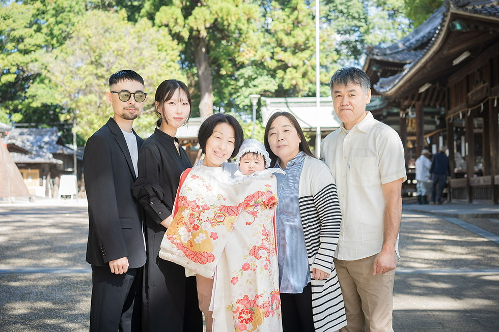 祝い着を掛けた赤ちゃんを囲む、お宮参りのご家族集合写真