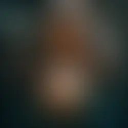 Mulher sorridente segurando flor de lótus iluminada em ambiente místico com luzes suaves ao fundo.