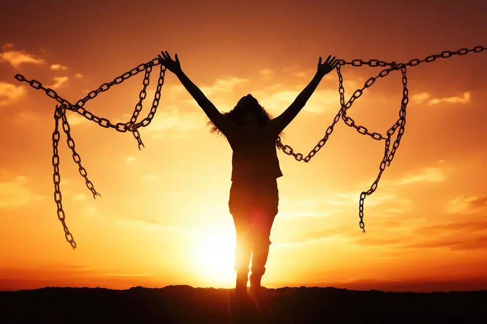 Pessoa em silhueta com correntes rompidas erguidas nos braços, simbolizando liberdade e superação ao pôr do sol.