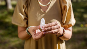 Mulher segurando cristal de quartzo transparente em ambiente natural, representando conexão espiritual, energia de cura e práticas de cristaloterapia.