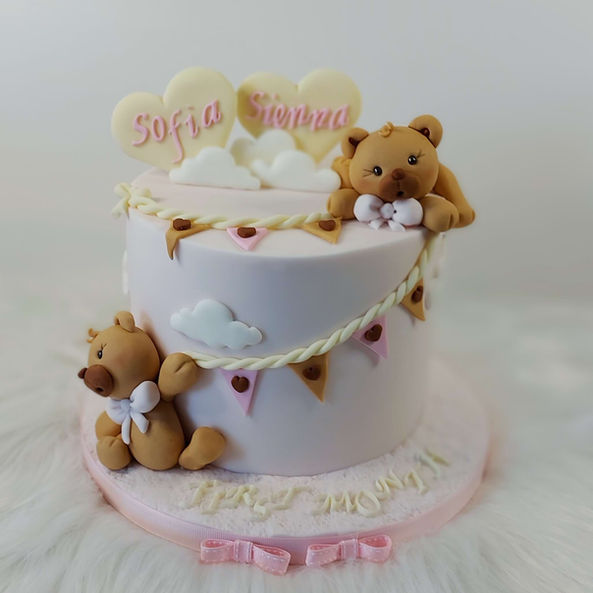 A soft pink fondant twins cake with two sweet bears as decorations.
