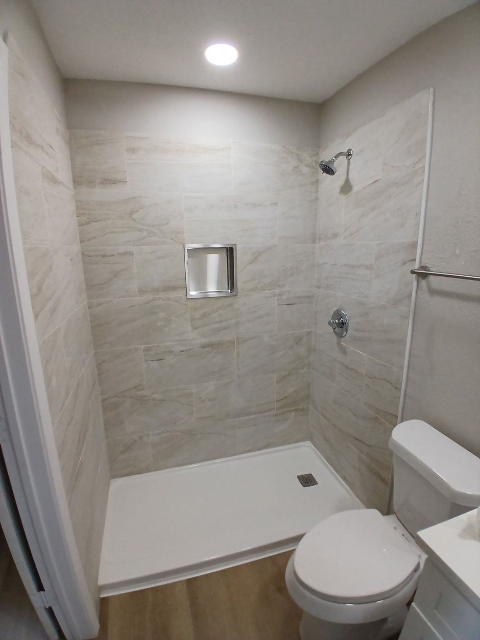 Tile shower with marble-look walls and recessed niche