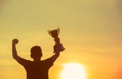 person with arms upraised, holding trophy