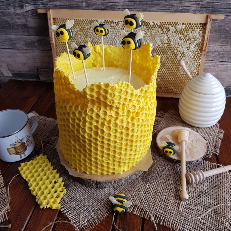 Eine Bienentorte mit Muster einer Wabe und kleinen Bienen auf Holzspießen