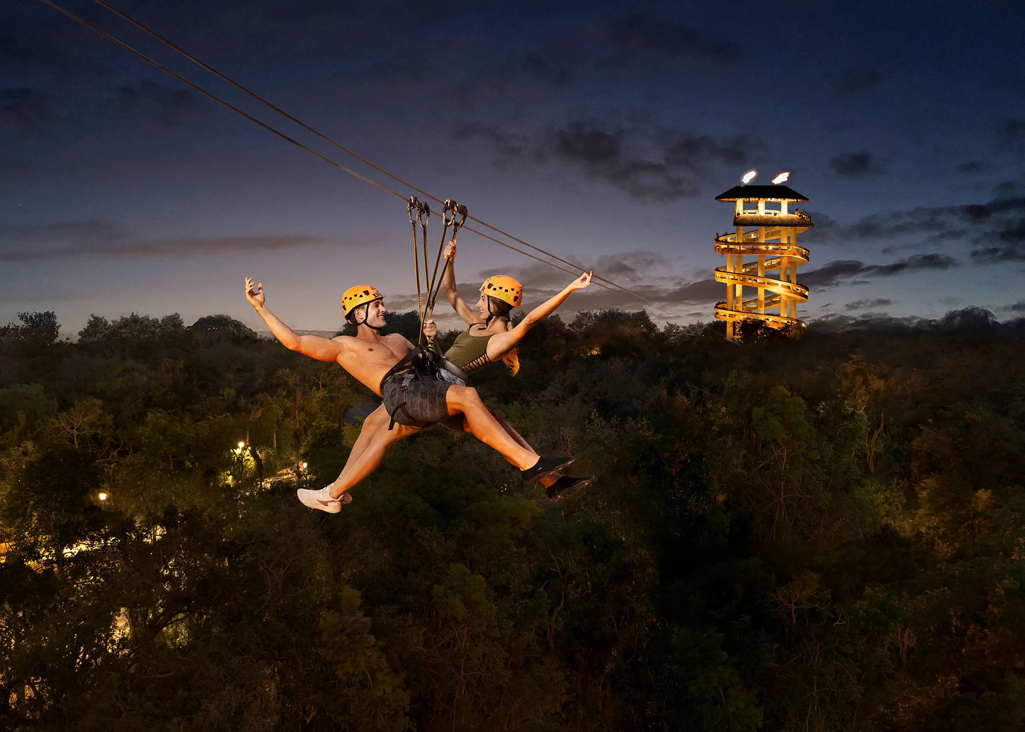 туристы летят на зиплайне ночью в парке иксплор
