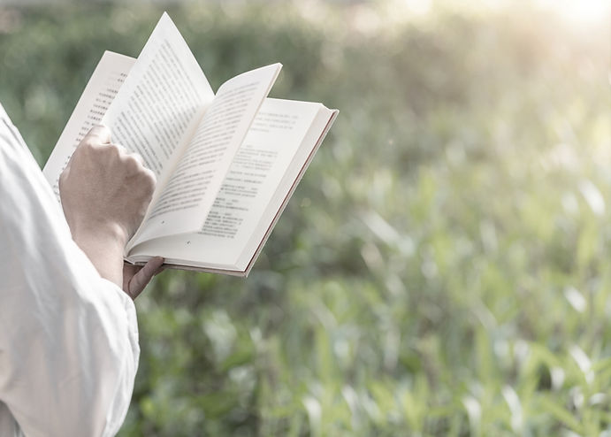 a person holding an open book reading passages