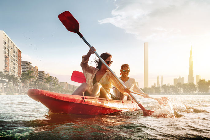 Residents kayaking on the crystal lagoon at Azizi Riviera, surrounded by modern apartments.