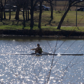 A rower quietly enjoys a beautiful day out on the lake.