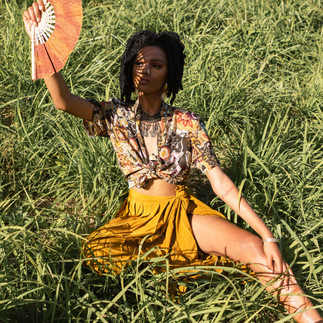Girl posing on grass with fan in her hand 