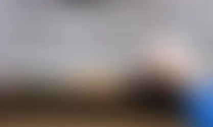 Hand cleaning leaves and debris from a roof gutter using a small tool.