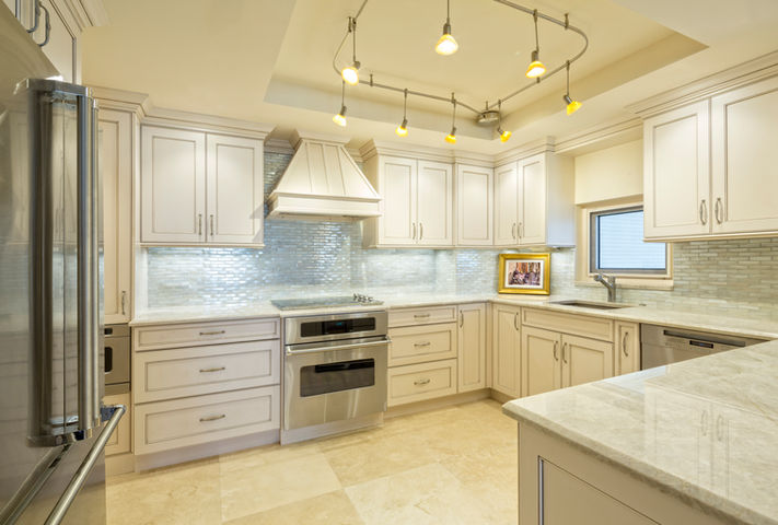 Kitchen with countertops,  cabinets, appliances, light-colored backsplash, and unique track lighting