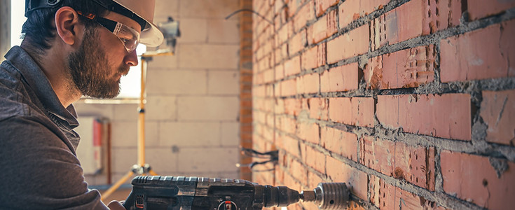 Worker using power tool on wall showing precise demolition and junk removal service