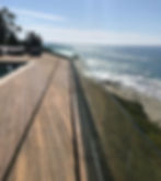 Frameless glass railing on a luxury wooden patio deck overlooking the ocean.
