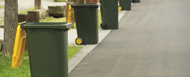 Row of waste bins outdoors showing organized junk removal and recycling management