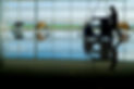 Janitor pushing a cart across a shiny airport terminal with reflection on the floor.