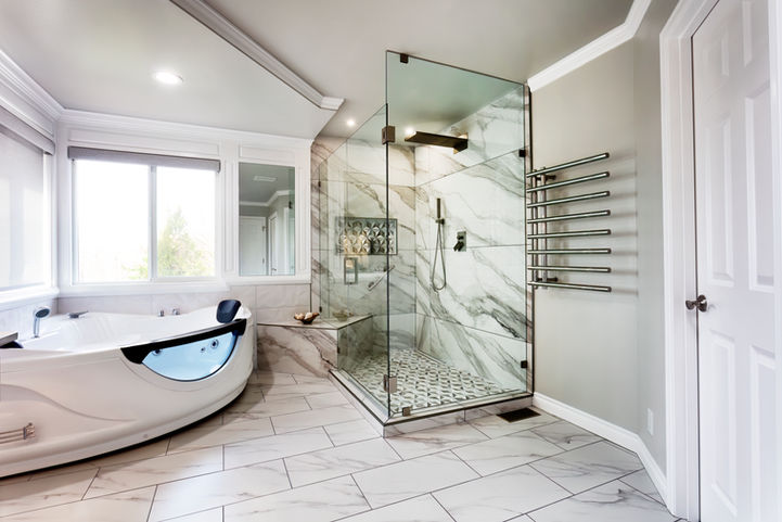 Modern bathroom with marble tile shower stall, jetted tub, and heated towel rack