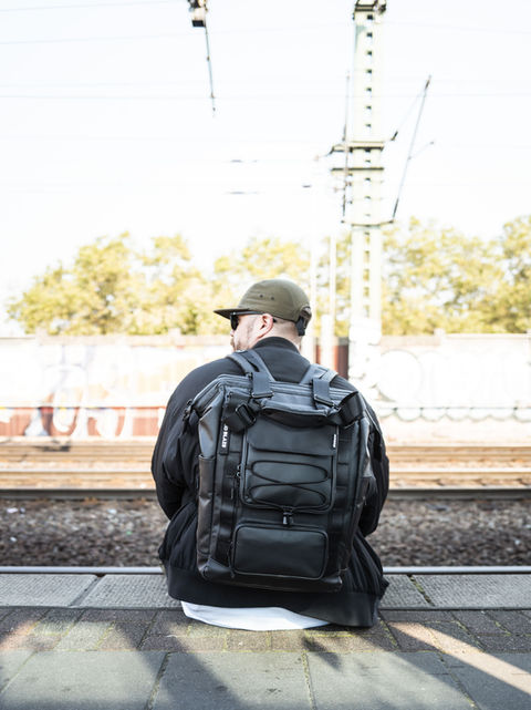 Man with Solid Blaze Tote Pack 85 sits on train platform