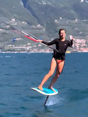 Frau beim Kitesurfen mit Bier in der Hand