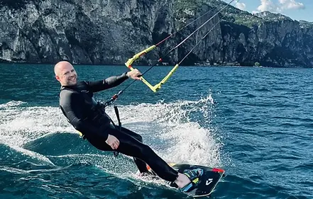 Kitesurfer am Gardasee der in die Kamera lacht.webp