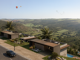 Modern single-storey homes with flat roofs overlooking a green valley