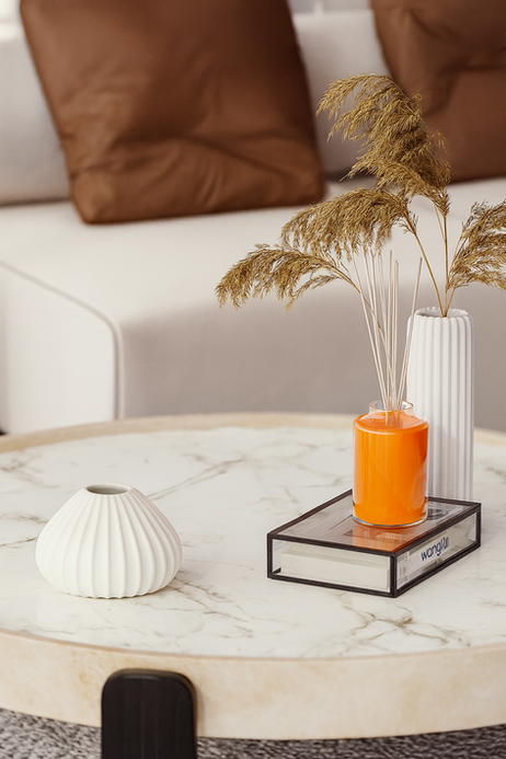 Minimalist coffee table decor with orange candle, pampas grass and white ceramic vases