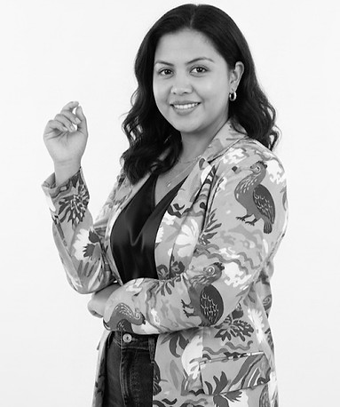 Professional black-and-white headshot of a smiling team member in a patterned blazer — company portrait