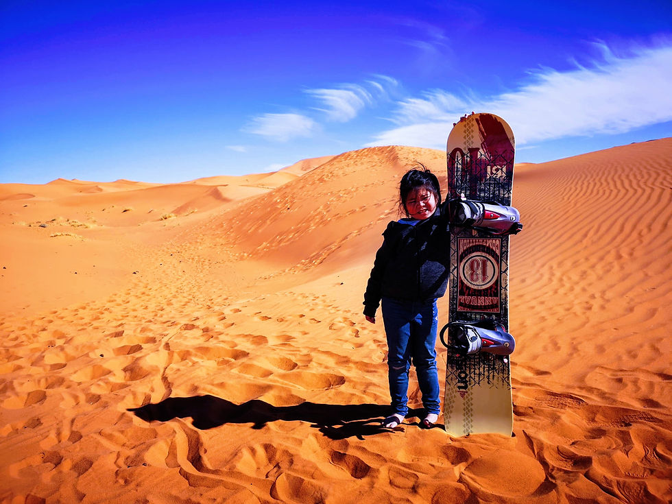 Little girl with sand board in Sahara Desert