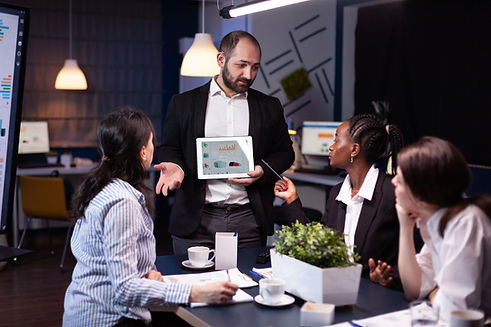 overworked-businessman-showing-financial-graphs-presentation-using-tablet-brainstorming-co