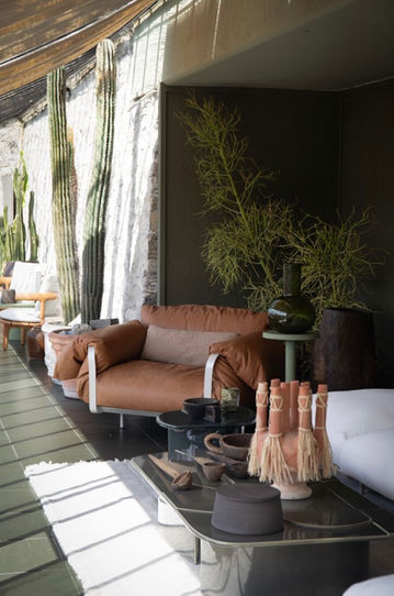 Baxter leather lounge chair and artisanal pottery on a stone villa terrace with greenery.